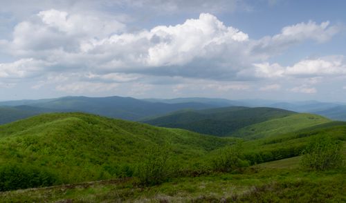 Free Expansive view of green hills and mountains under a cloudy sky, perfect for nature enthusiasts. Stock Photo