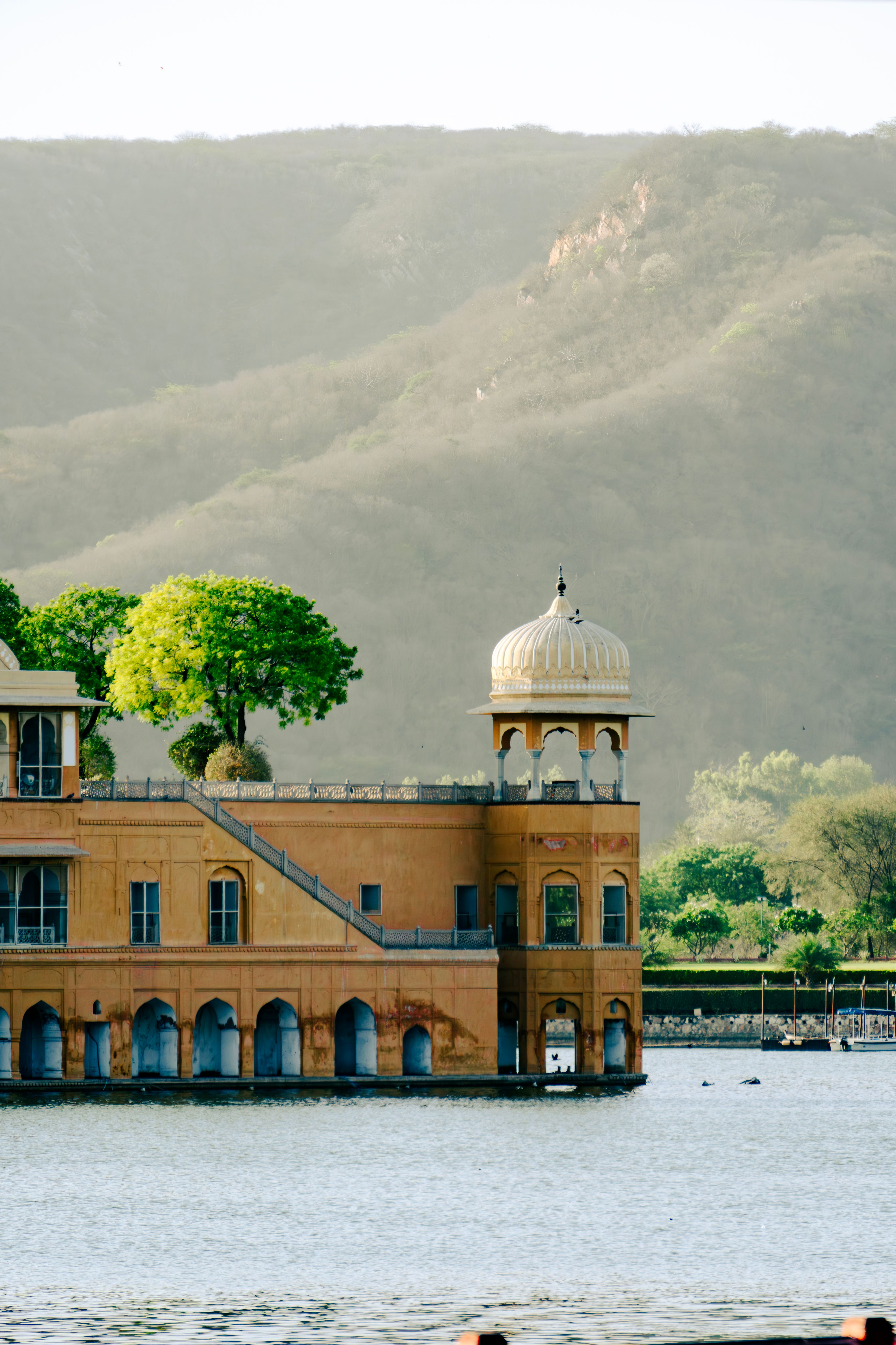 Scenic view of Jal Mahal Palace on Man Sagar Lake in Jaipur, India, surrounded by serene mountains.
