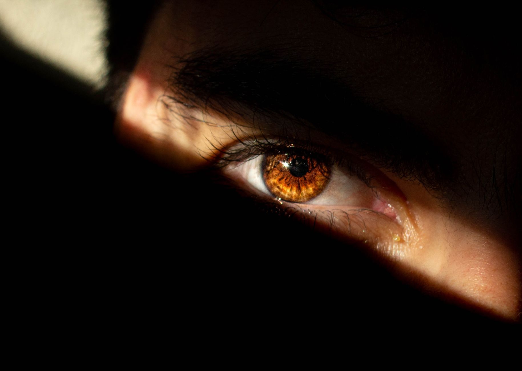 A striking close-up of a human eye partially covered by shadows with intense focus.