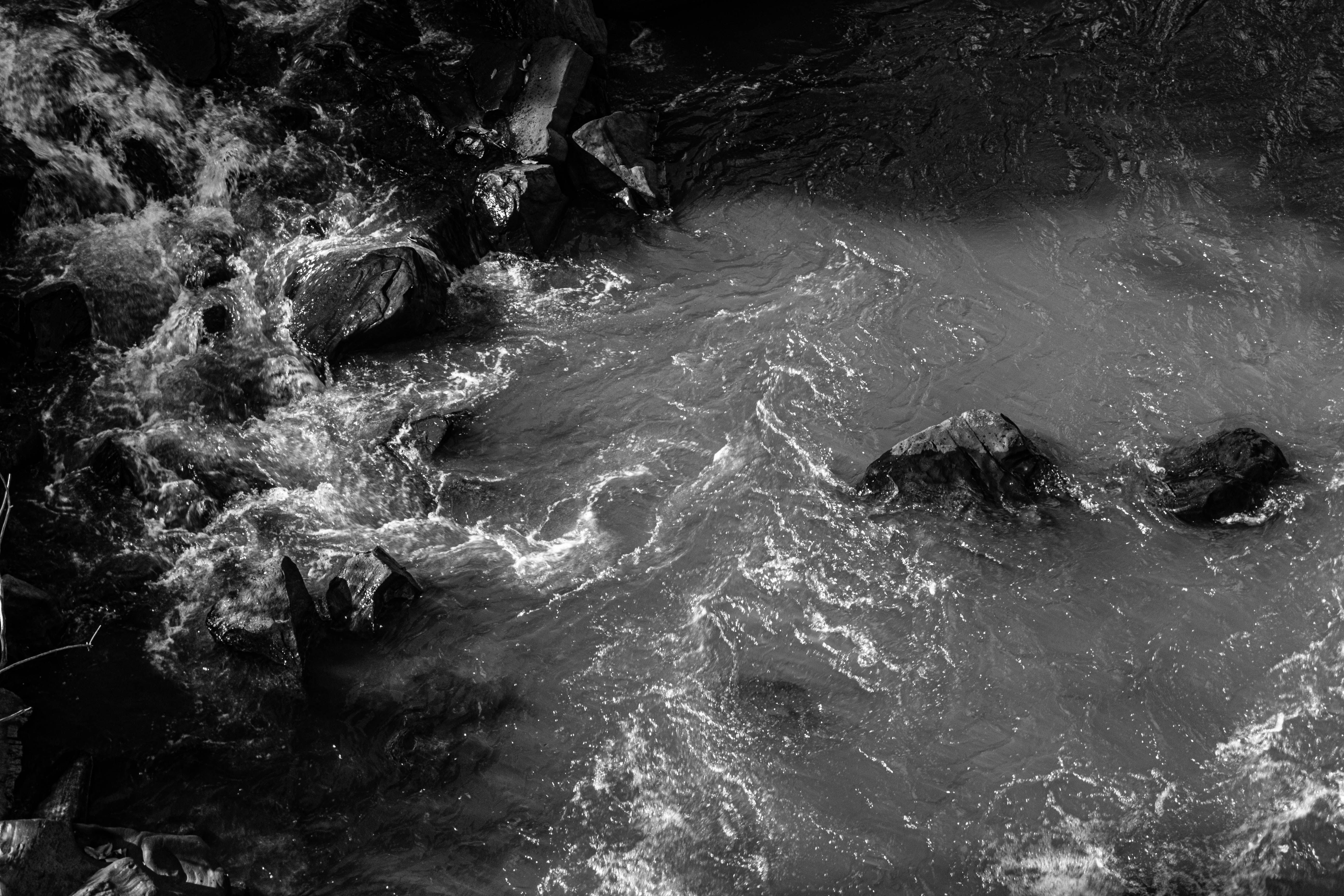 A striking black and white photo capturing the motion of river water flowing over rocks.