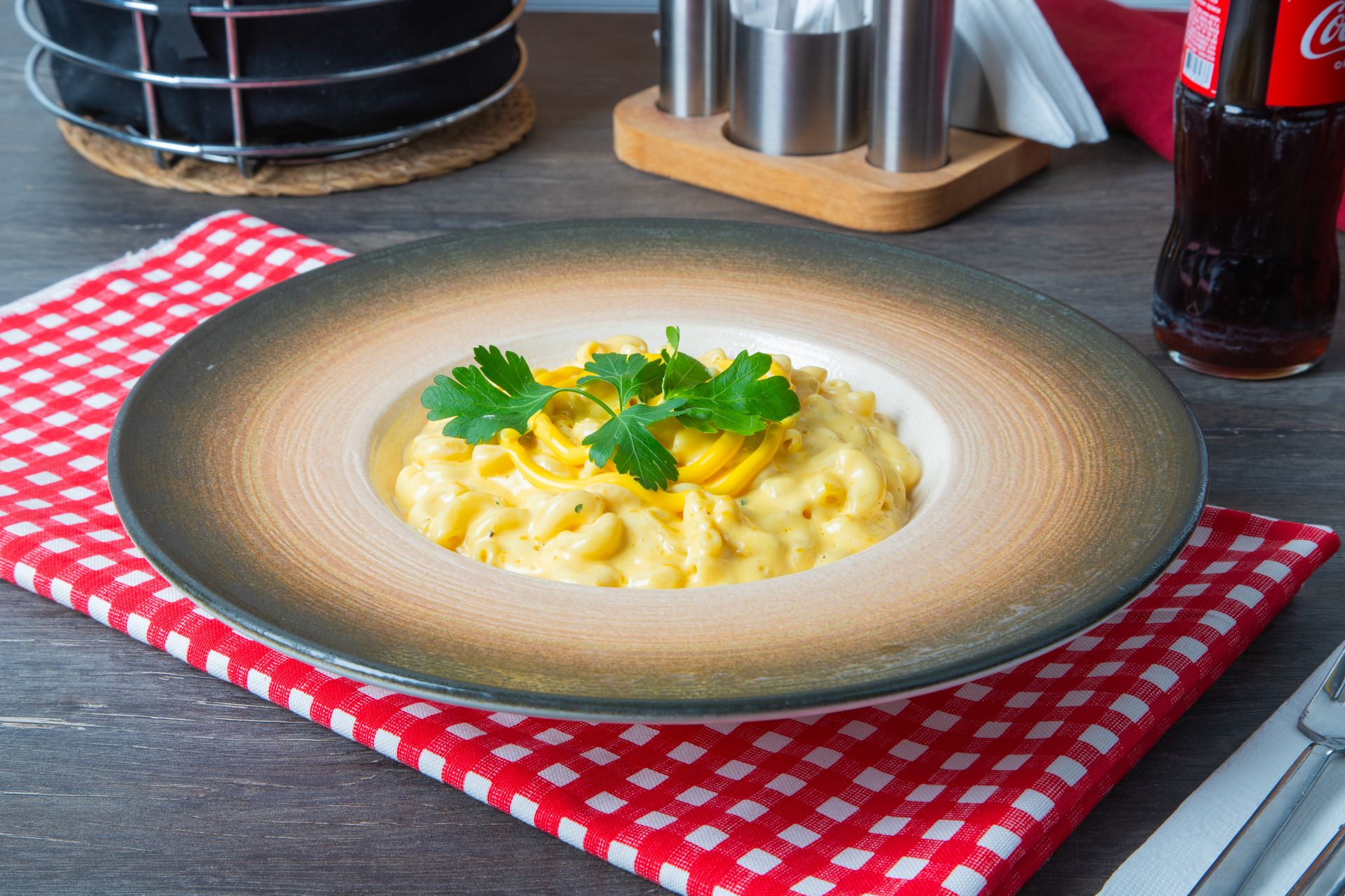 Delicious mac and cheese garnished with parsley on a checkered tablecloth.