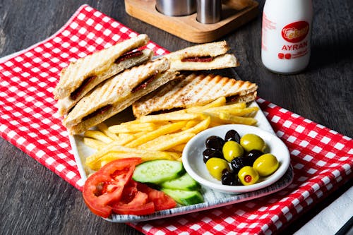 A plate with a sandwich, fries and olives