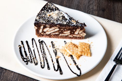 A piece of chocolate cake with chocolate sauce and crackers