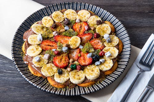 A plate with a pizza topped with fruit and nuts