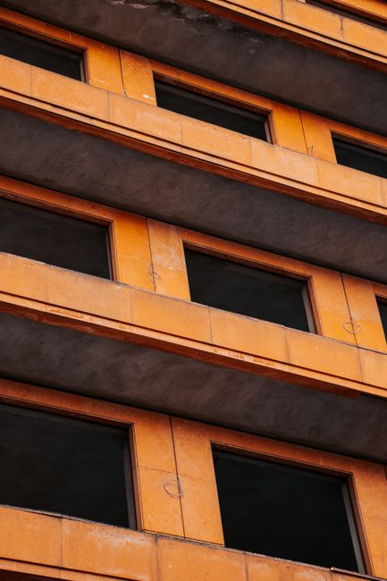 Close-up of a modern building with orange facades and balconies, showcasing urban architecture.