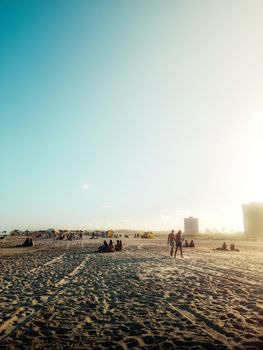 People enjoying a sunny day on a beach with high-rise buildings in the distance. Perfect for travel and holiday themes.