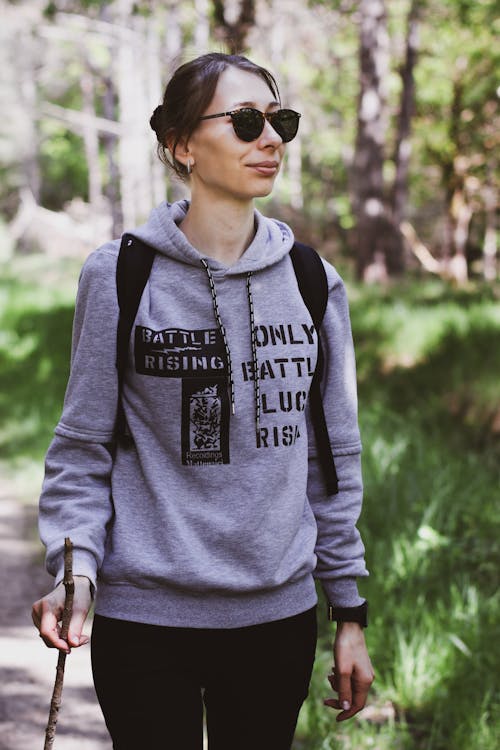 A woman walking in the woods wearing a hoodie