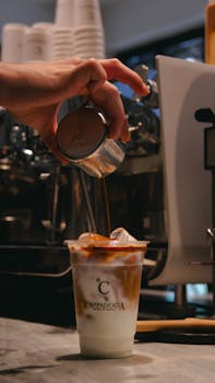 Barista pouring coffee into a disposable cup with ice, Cappadocia Café branded.