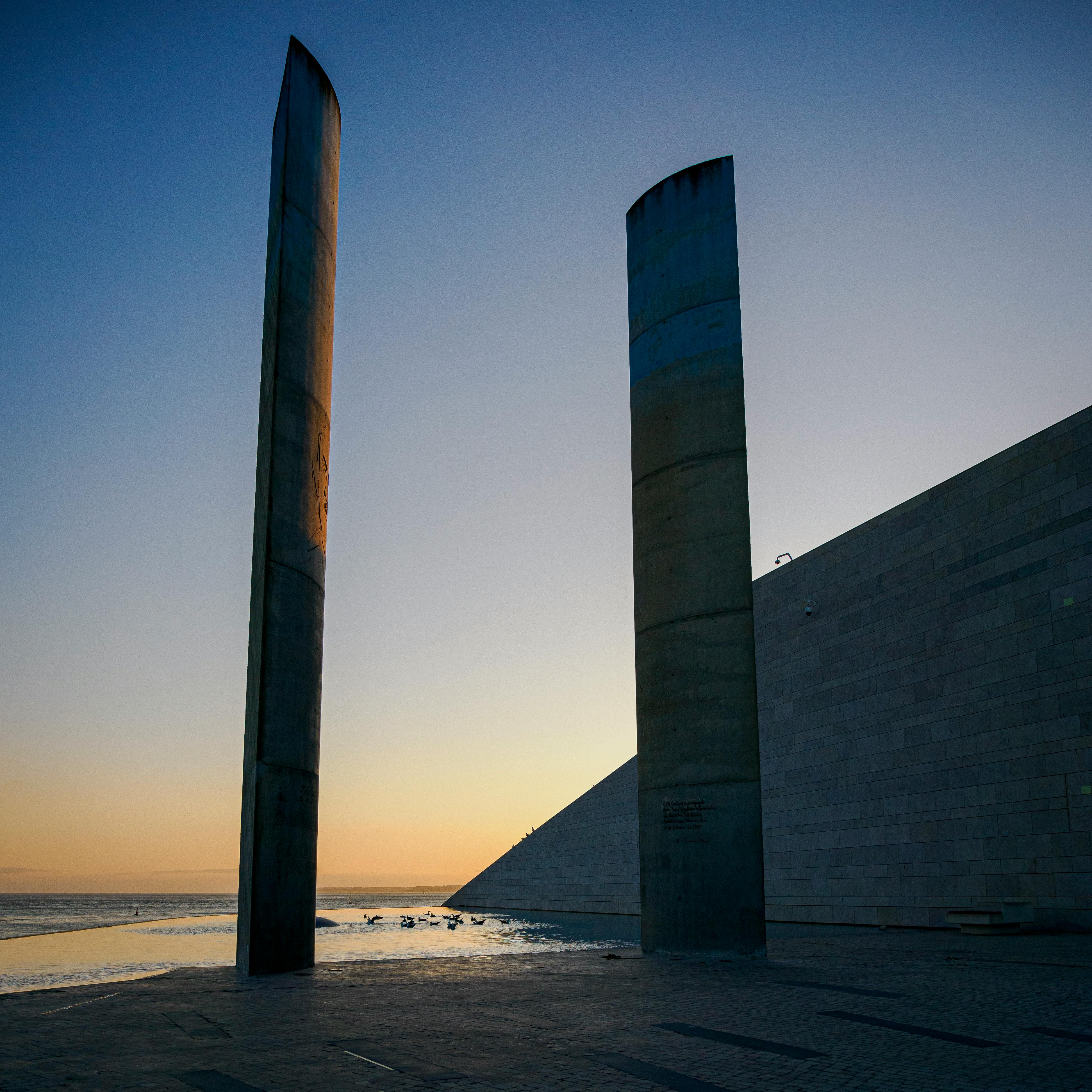 silhouette of poles by the shore during sunset