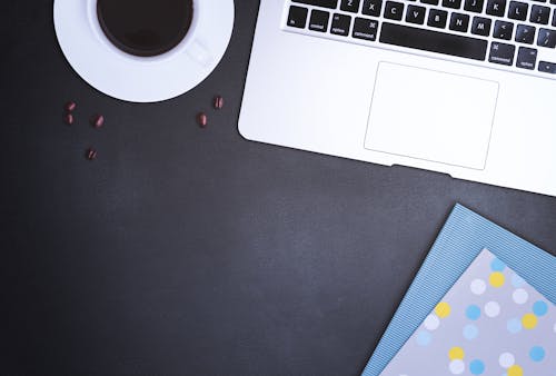 Flat Lay Photography of Macbook Beside Adhesive Tape and Scattered Coffee Beans