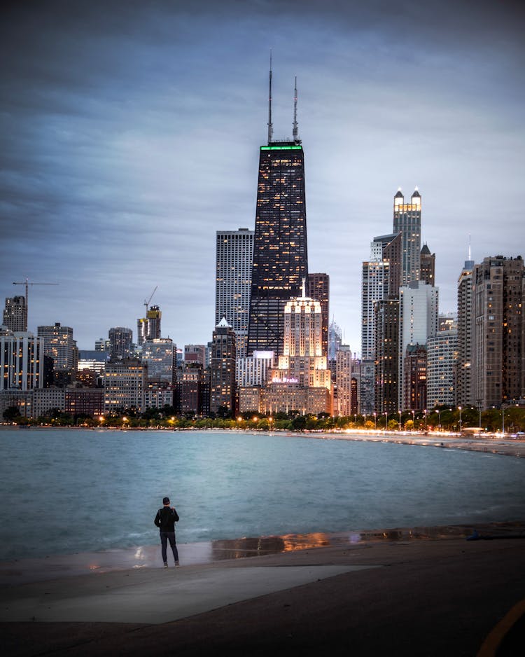 Person Standing Near The Sea Watching Buildings