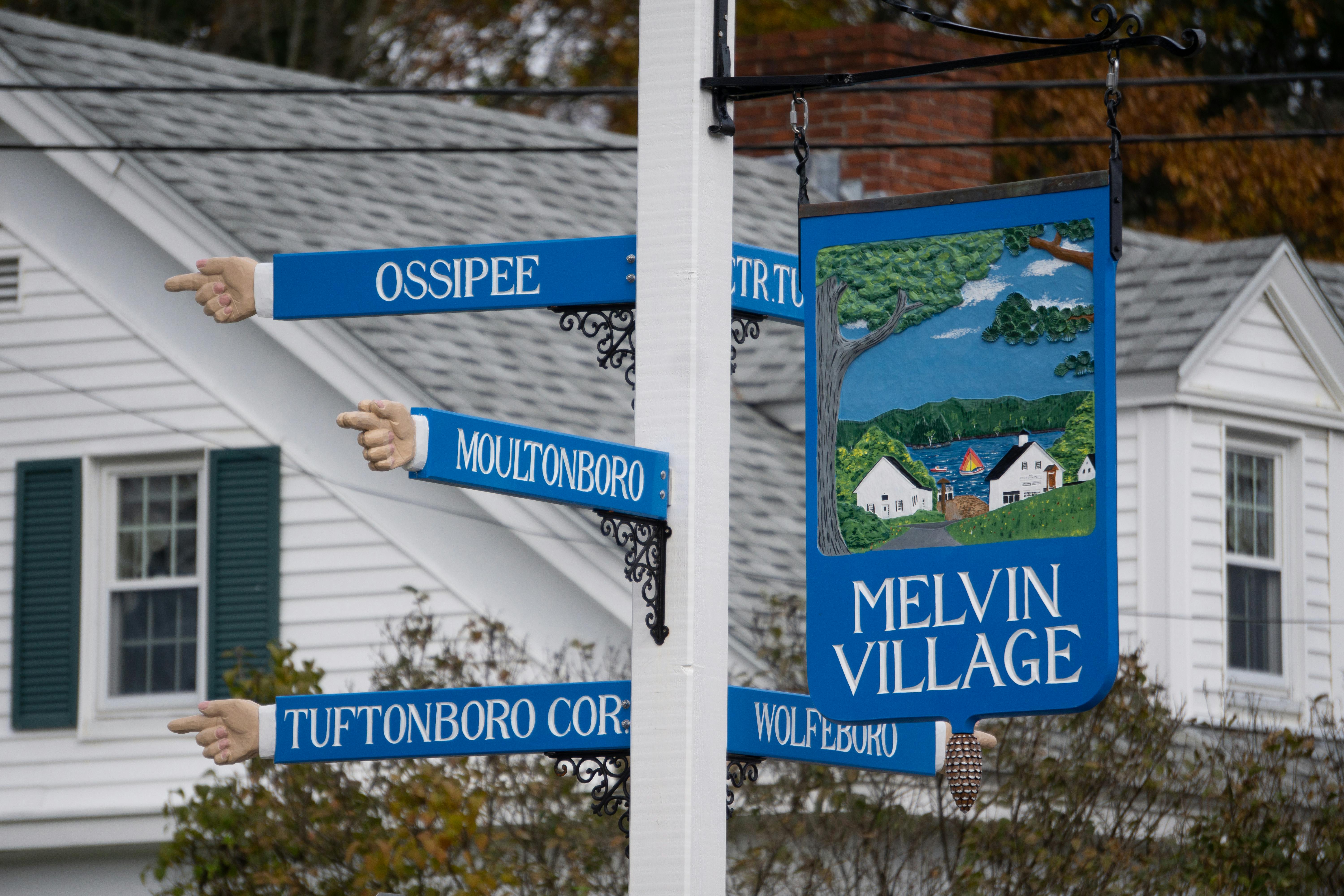 Colorful directional sign pointing to various locations in rural Melvin Village, NH.