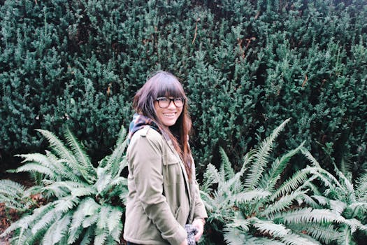 一位戴眼镜、留着刘海的女士在绿树成荫的公园里微笑