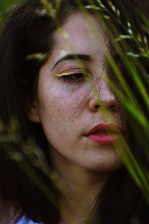 Foto De Retrato De Close Up De Mulher Atrás De Uma Planta De Folhas Verdes Olhando Para Longe