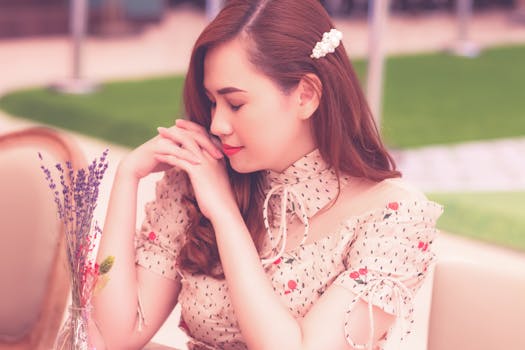 一位年轻女子闭着眼睛，表情安详，在户外摆出体贴的姿势