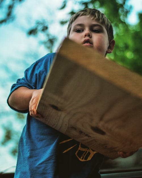 Free Low Angle Photo of Boy Holding Wooden Panel Stock Photo