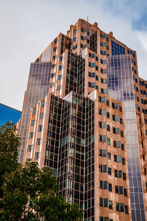 Free Dramatic view of a modern skyscraper with mirrored windows and urban surroundings. Stock Photo