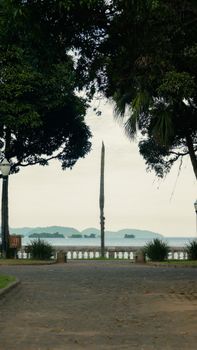 Tranquil view of Antonina Bay through lush park with tall trees and obelisk.
