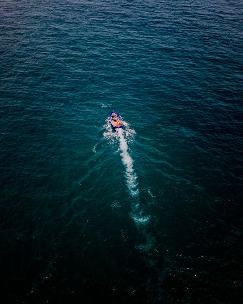 Free A vibrant speedboat cutting through the deep ocean off the coast of Morocco, creating a striking water trail. Stock Photo