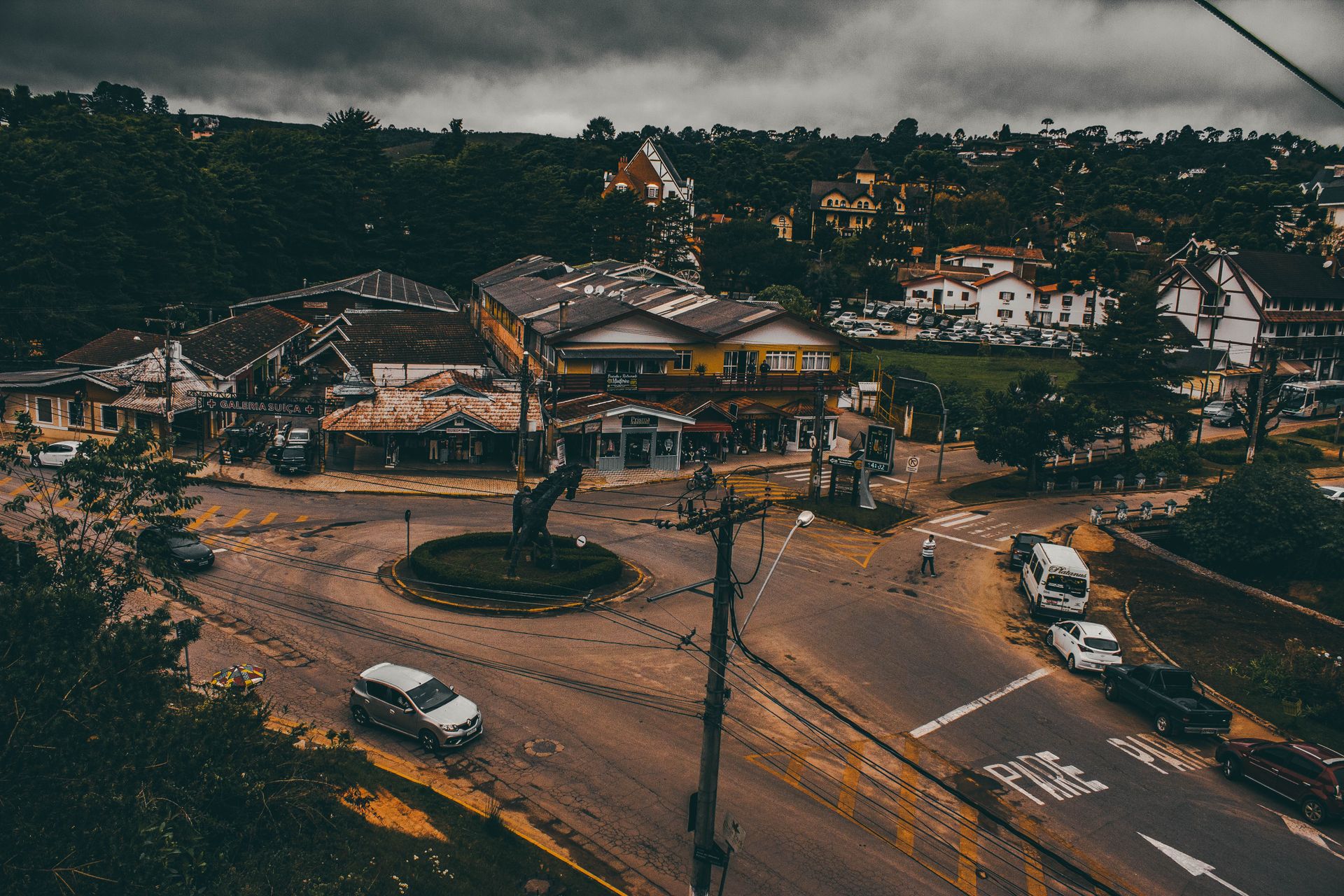 Aerial shot of a roundabout in a small town under dark, dramatic clouds.