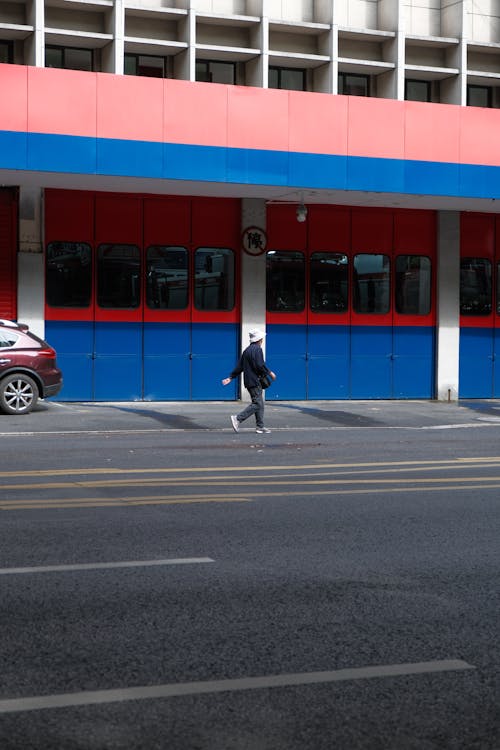 A person walking down the street in front of a red and blue building