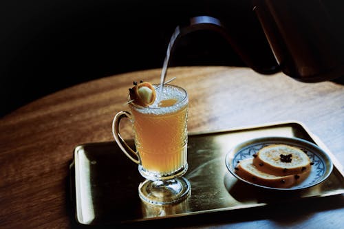 A person pouring a drink into a glass on a tray