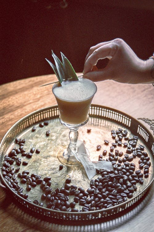 A person is holding a drink with coffee beans on it