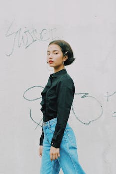 一名年轻女子穿着休闲装，自信地靠在涂鸦墙上摆出姿势