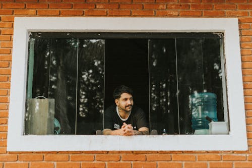 A man sitting in a window looking out