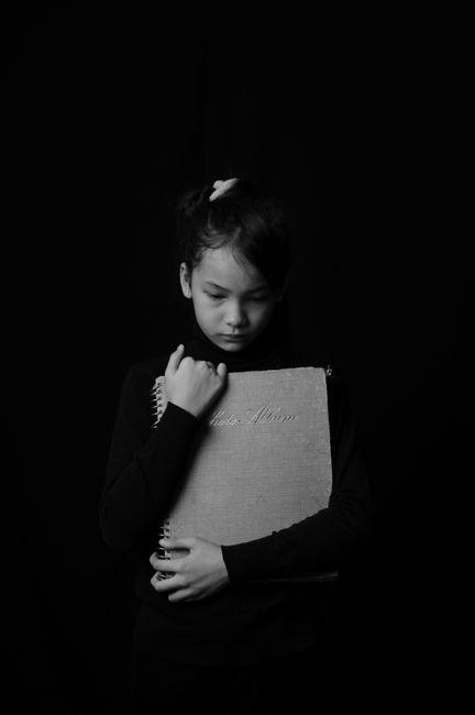 A monochrome image of a child holding a book, expressing deep emotion.