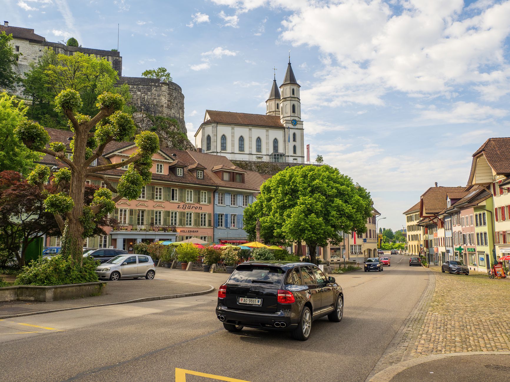 Charming street scene in historic Aarburg, Switzerland, featuring classic architecture and a church.