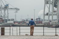 一名男子在雾气弥漫的工业港口凝望着货船