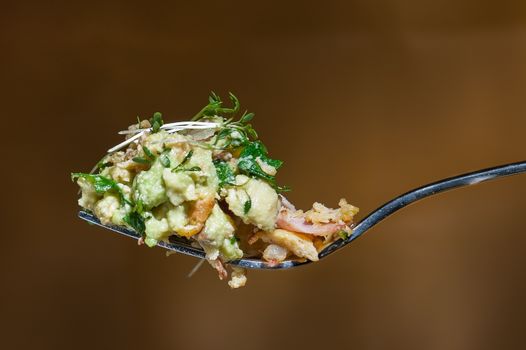 Appetizing close-up of a vibrant avocado salad served on a spoon, highlighting fresh ingredients.