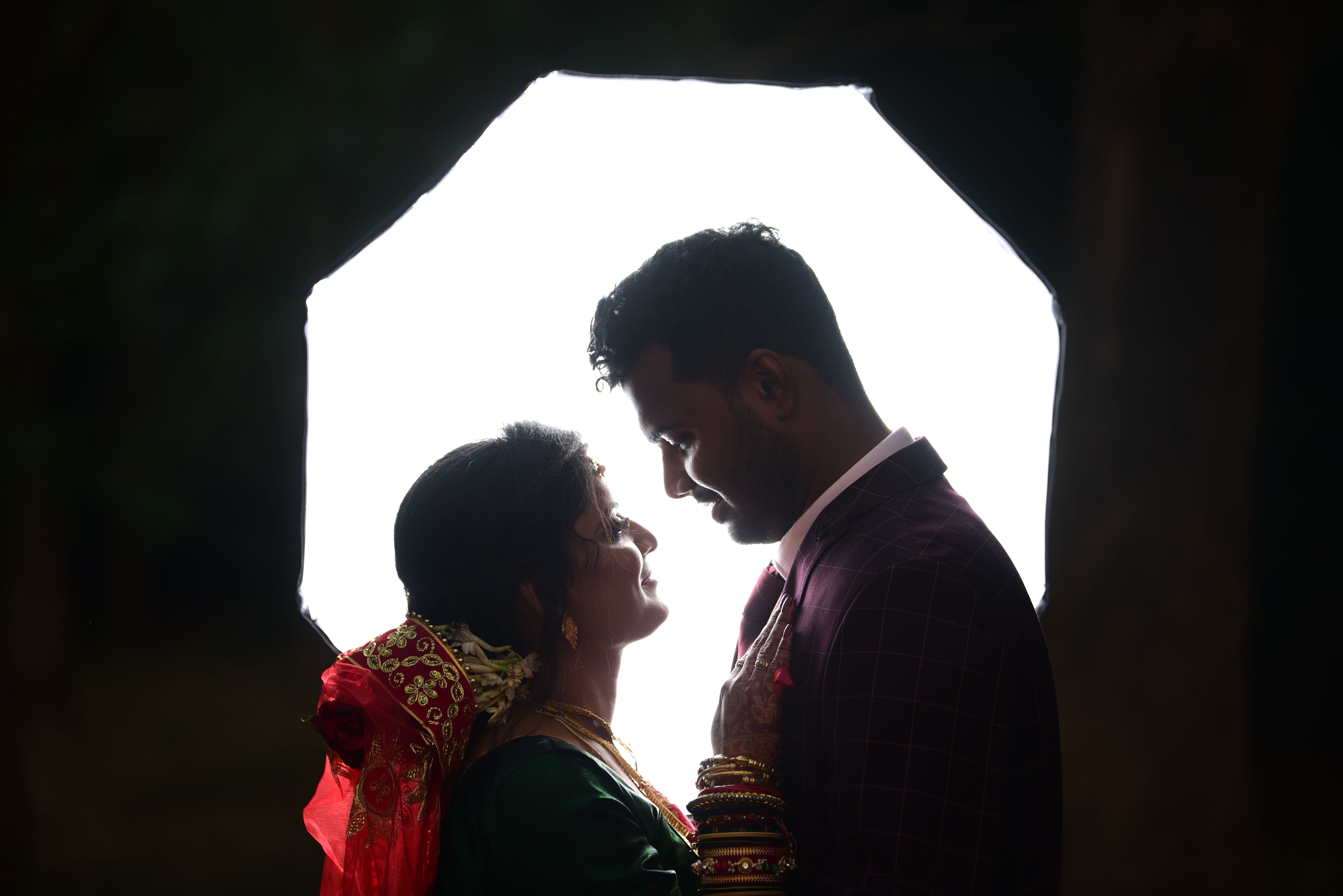 A beautiful silhouette of an Indian couple sharing a romantic gaze in traditional clothing.