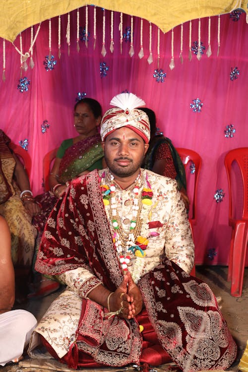 A man in traditional attire sitting in a wedding