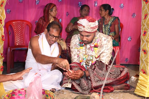 A man and woman are sitting on a stage with other people