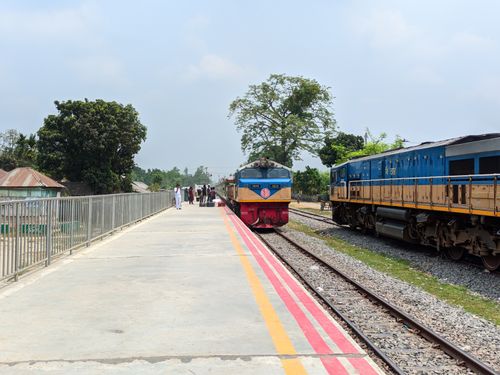 Free Colorful passenger train arriving at a rural train station platform on a sunny day with clear skies. Stock Photo
