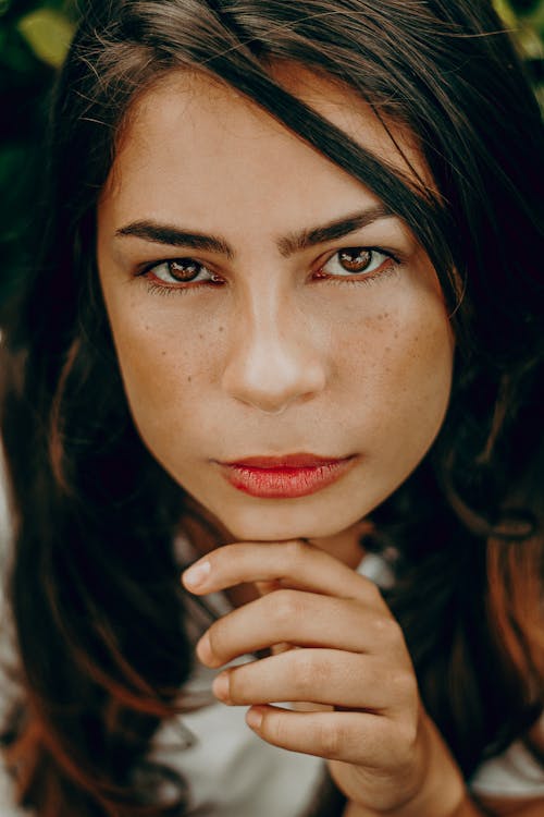 Close-up Portrait Photo of Woman Posing With Her Hand on Her Chin While Looking Up 