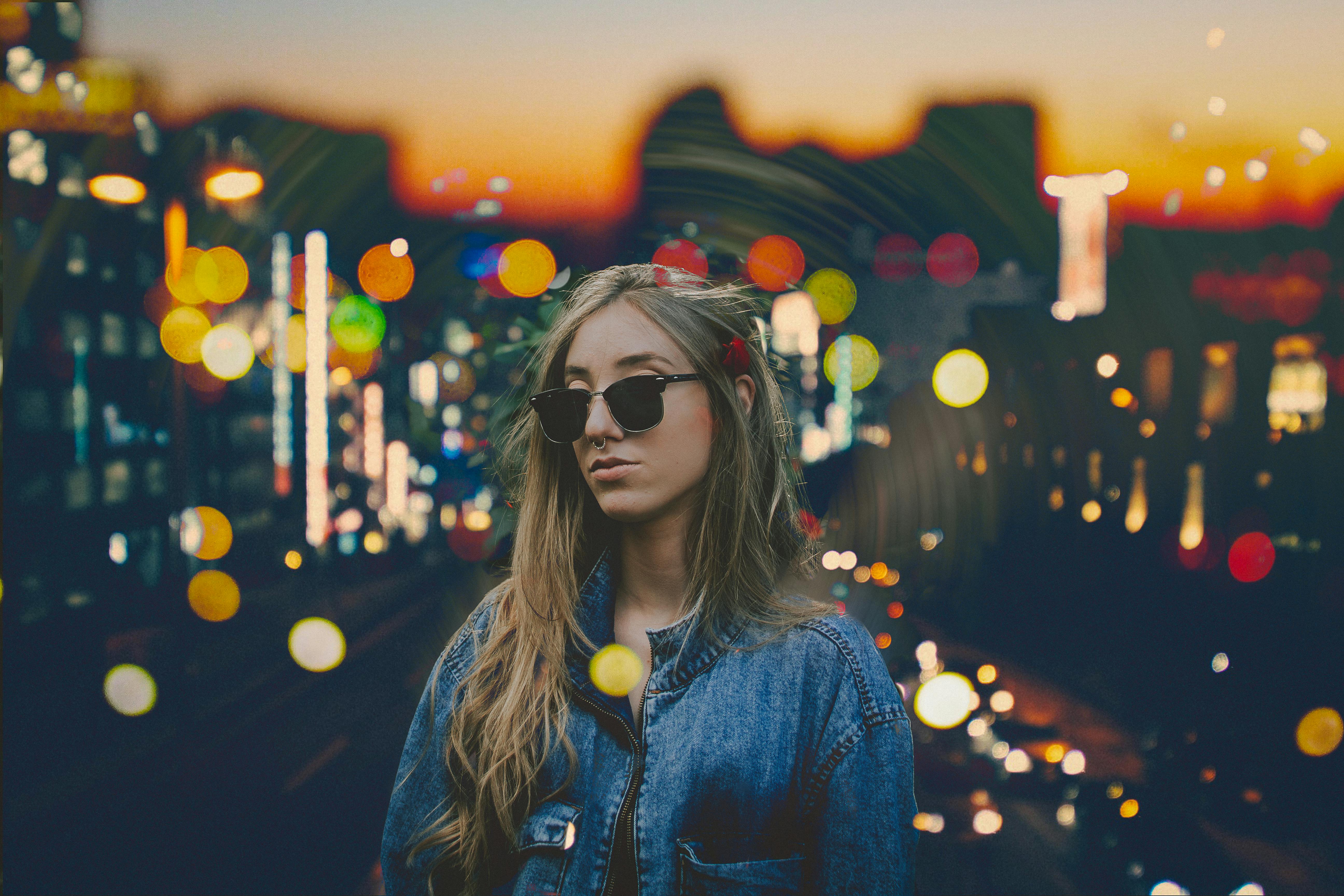 Portrait of a fashionable woman in streetwear at sunset with vibrant city lights in S&atilde;o Paulo.