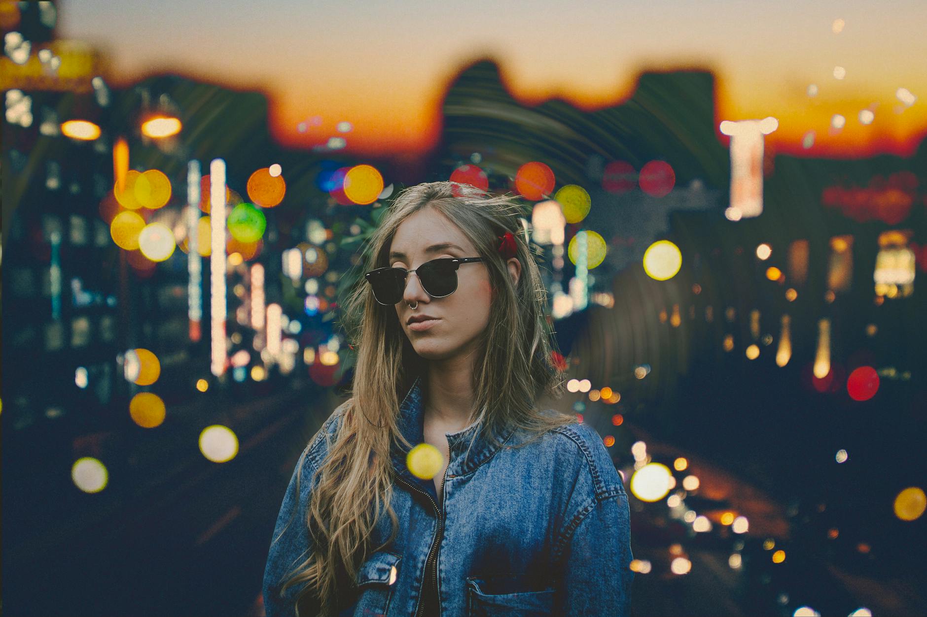 Portrait of a fashionable woman in streetwear at sunset with vibrant city lights in São Paulo.
