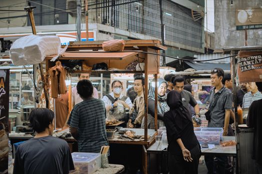 Crowded street market scene with diverse individuals engaging in street food trade, highlighting urban life.
