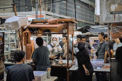 Free Crowded street market scene with diverse individuals engaging in street food trade, highlighting urban life. Stock Photo
