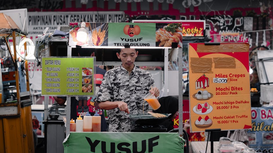 Asian street food vendor preparing telur gulung in a busy market stall.