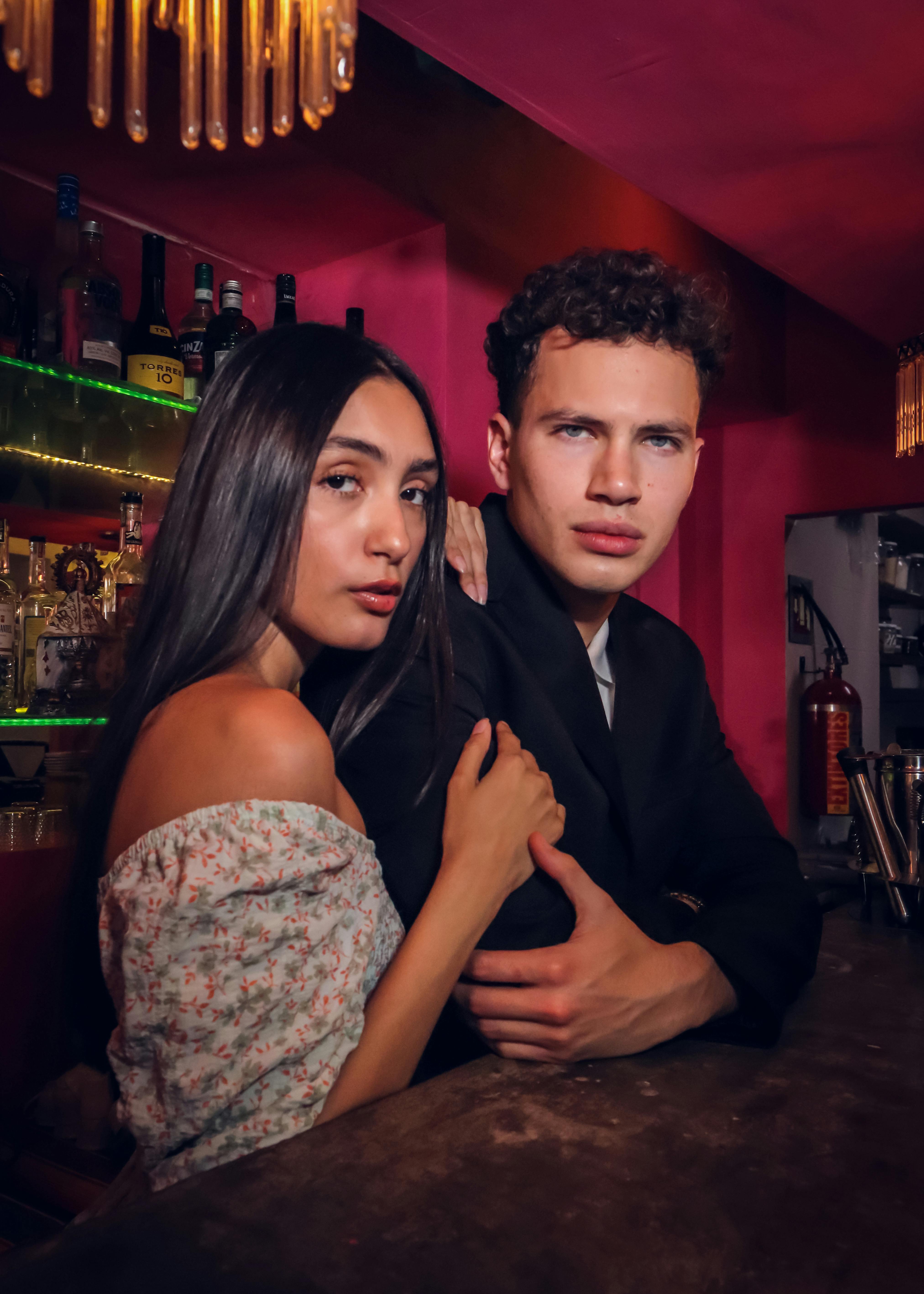 Young couple embracing at a vibrant bar, showcasing nightlife and style.