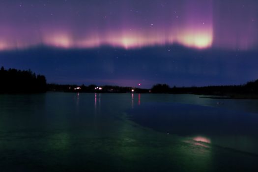Beautiful view of the Northern Lights over a tranquil lake in Jönköping, Sweden at night.