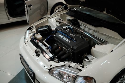 Detailed close-up of a Mugen-tuned Honda engine in a white car, showcasing automotive performance.