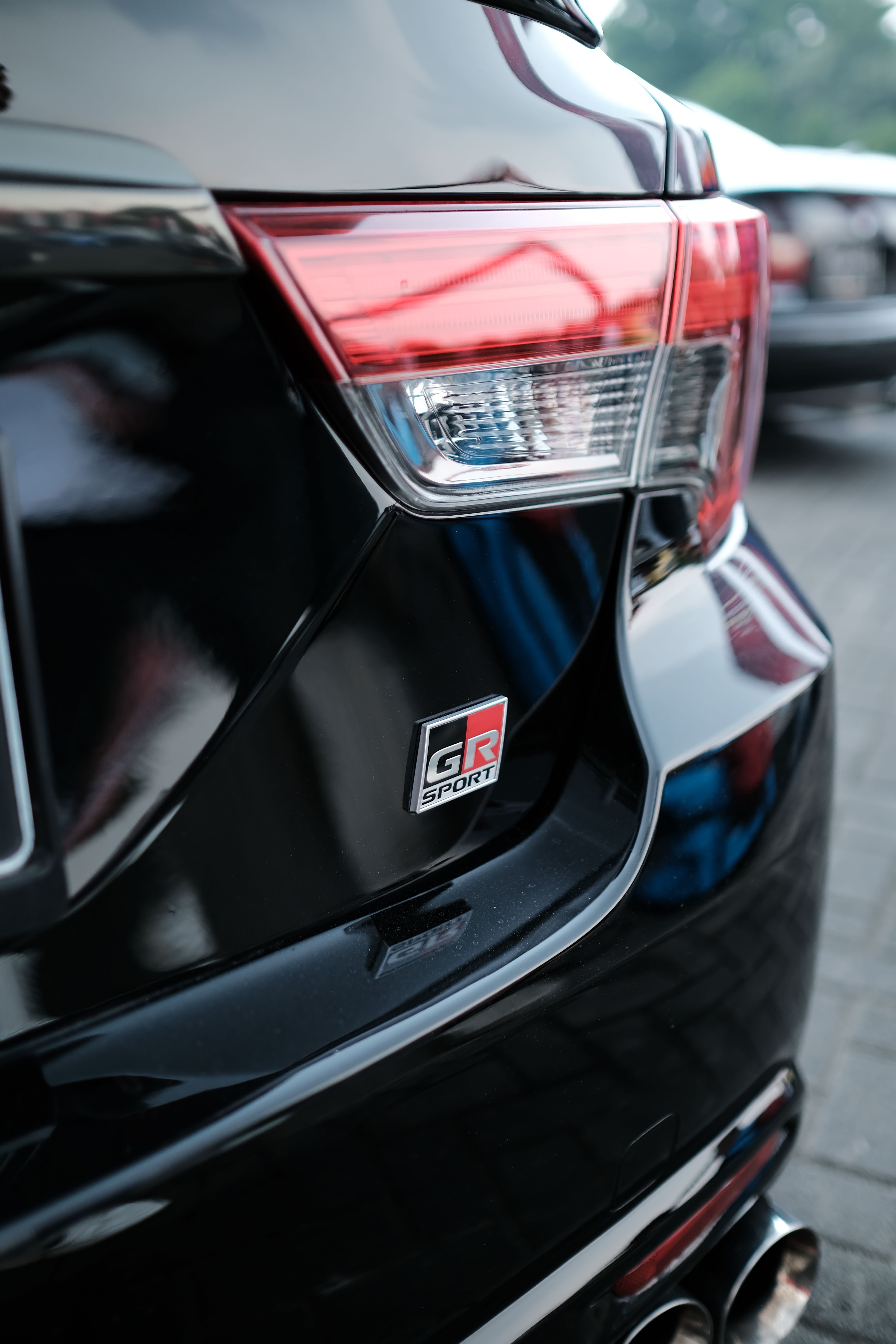 Close-up shot of a Toyota GR Sport badge on a glossy black car, emphasizing modern design.