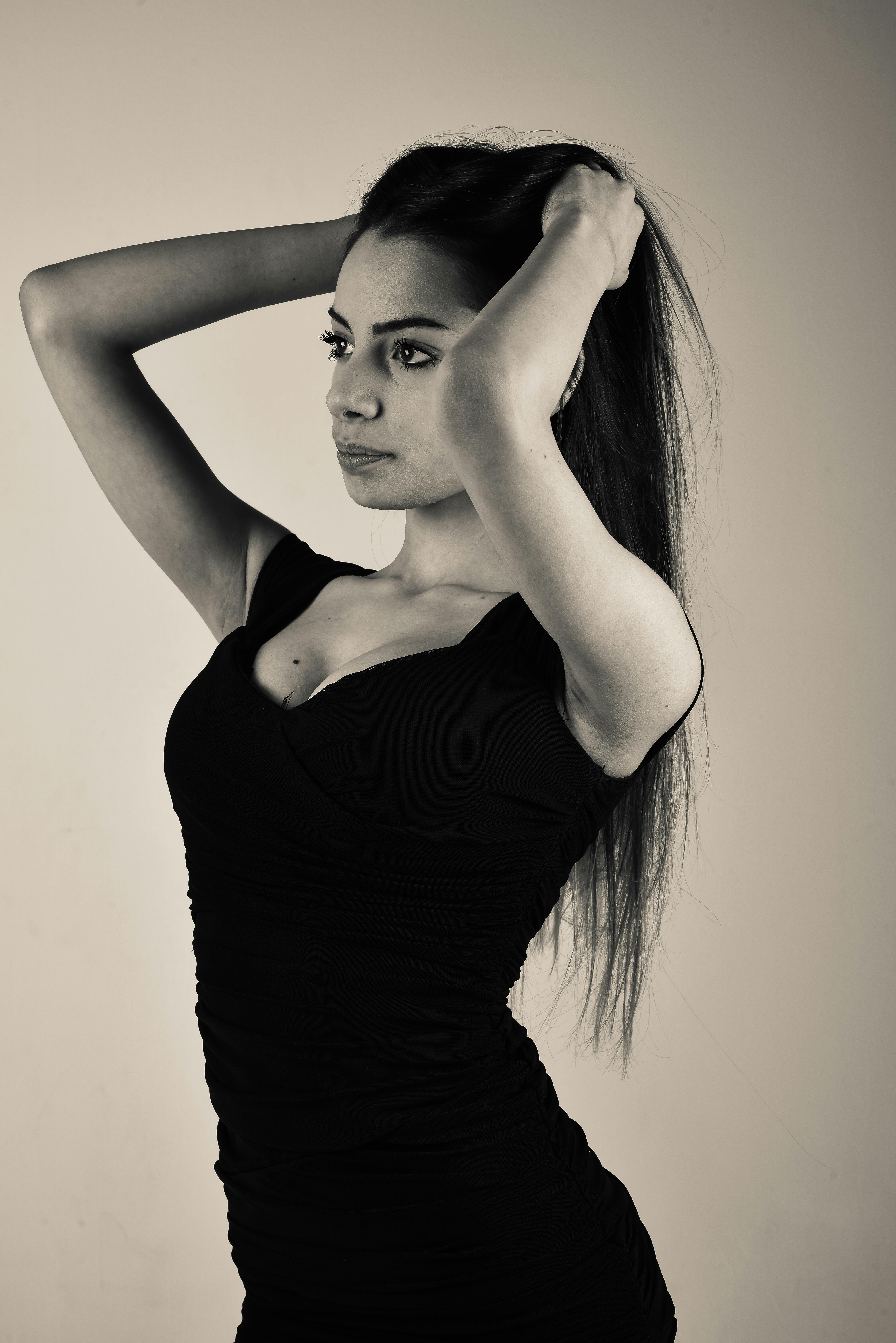 Striking studio portrait of a woman fixing her hair in a bodycon dress.