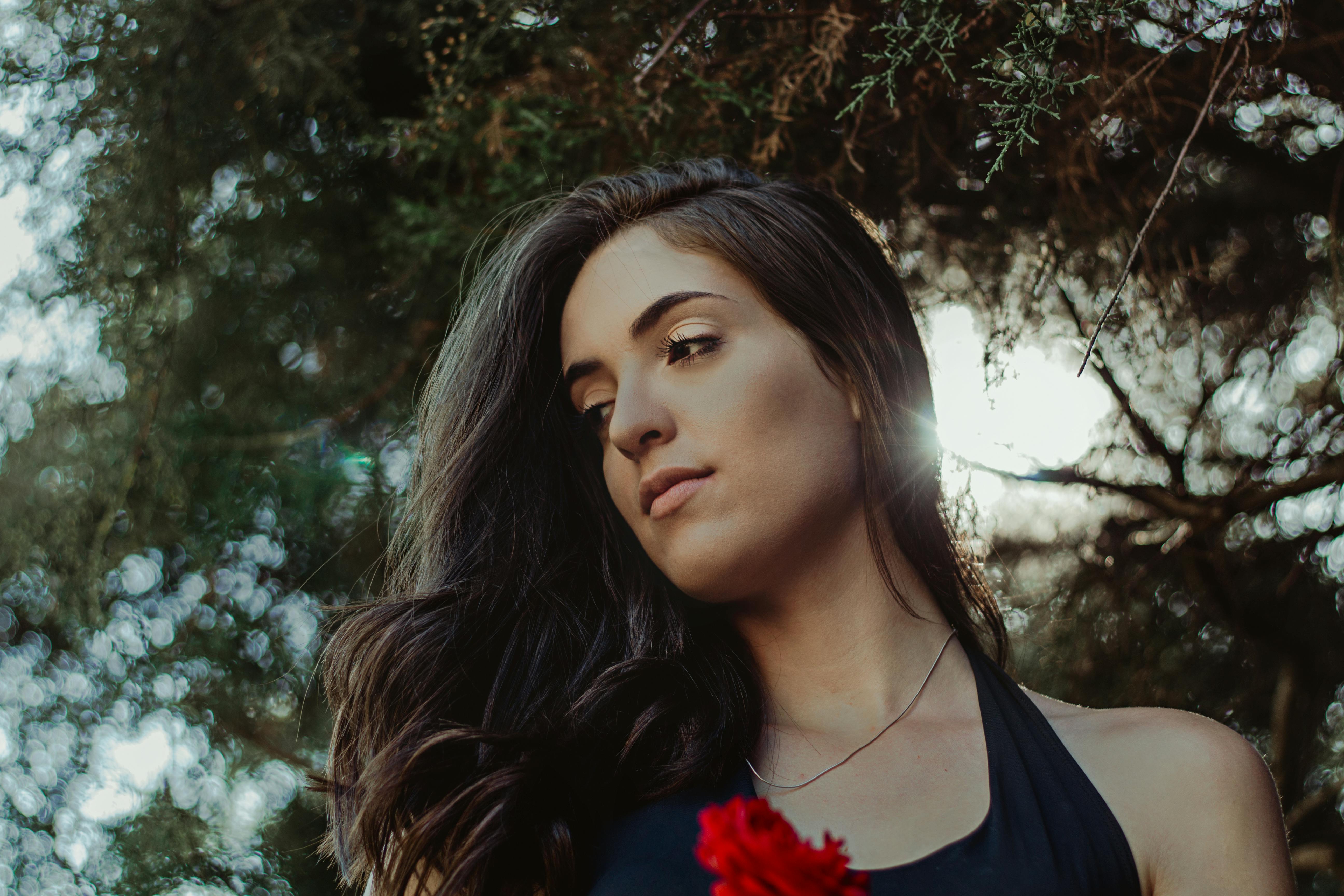 在自然环境中，阳光轻柔地照亮了一位长发女性的优雅肖像，展现了完美生活方式与时尚主题