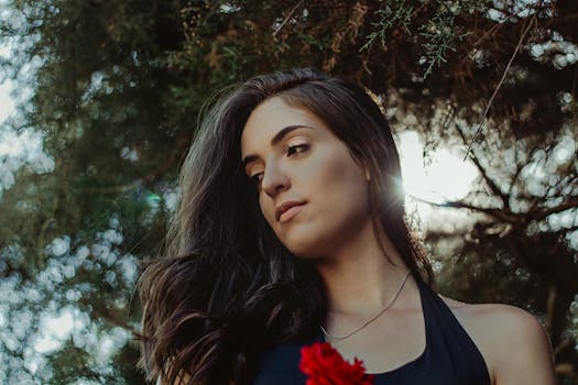 在自然环境中，阳光轻柔地照亮了一位长发女性的优雅肖像，展现了完美生活方式与时尚主题